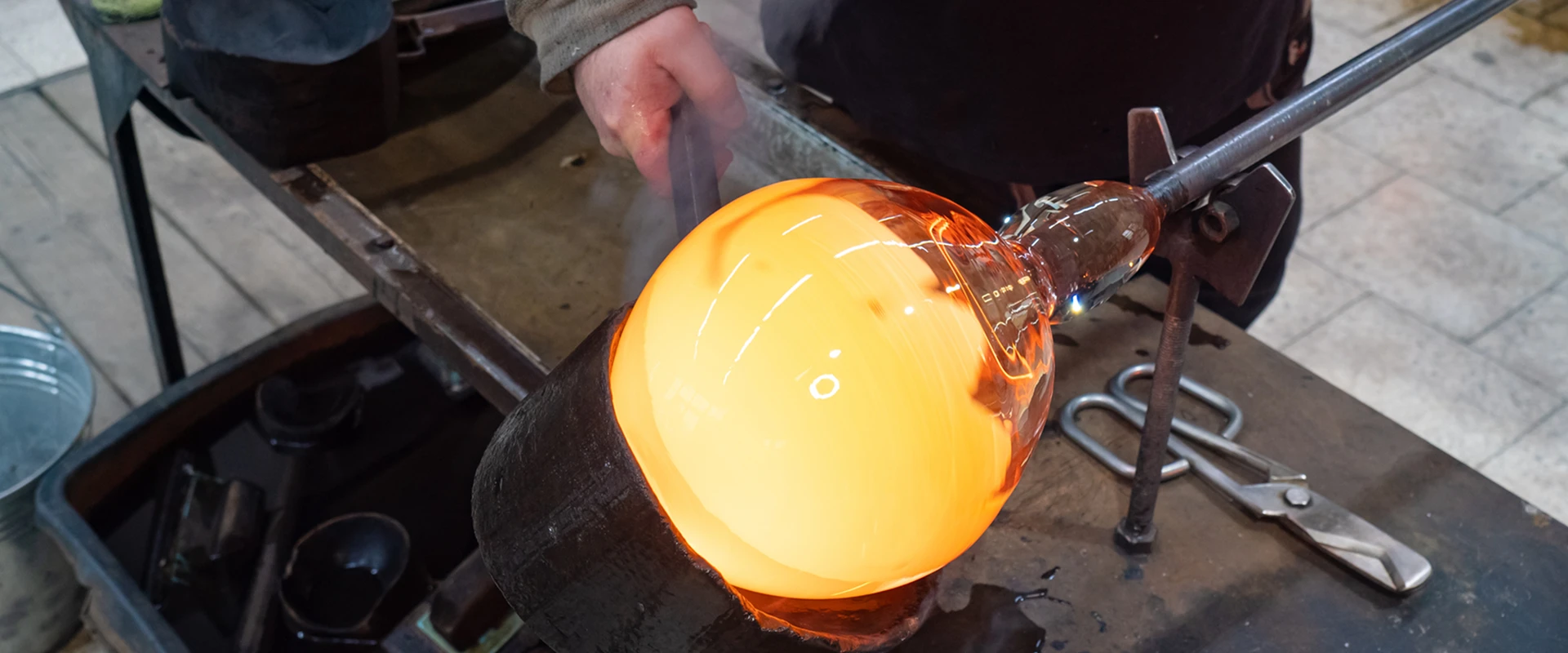 Glassblowing process with glowing molten glass.
